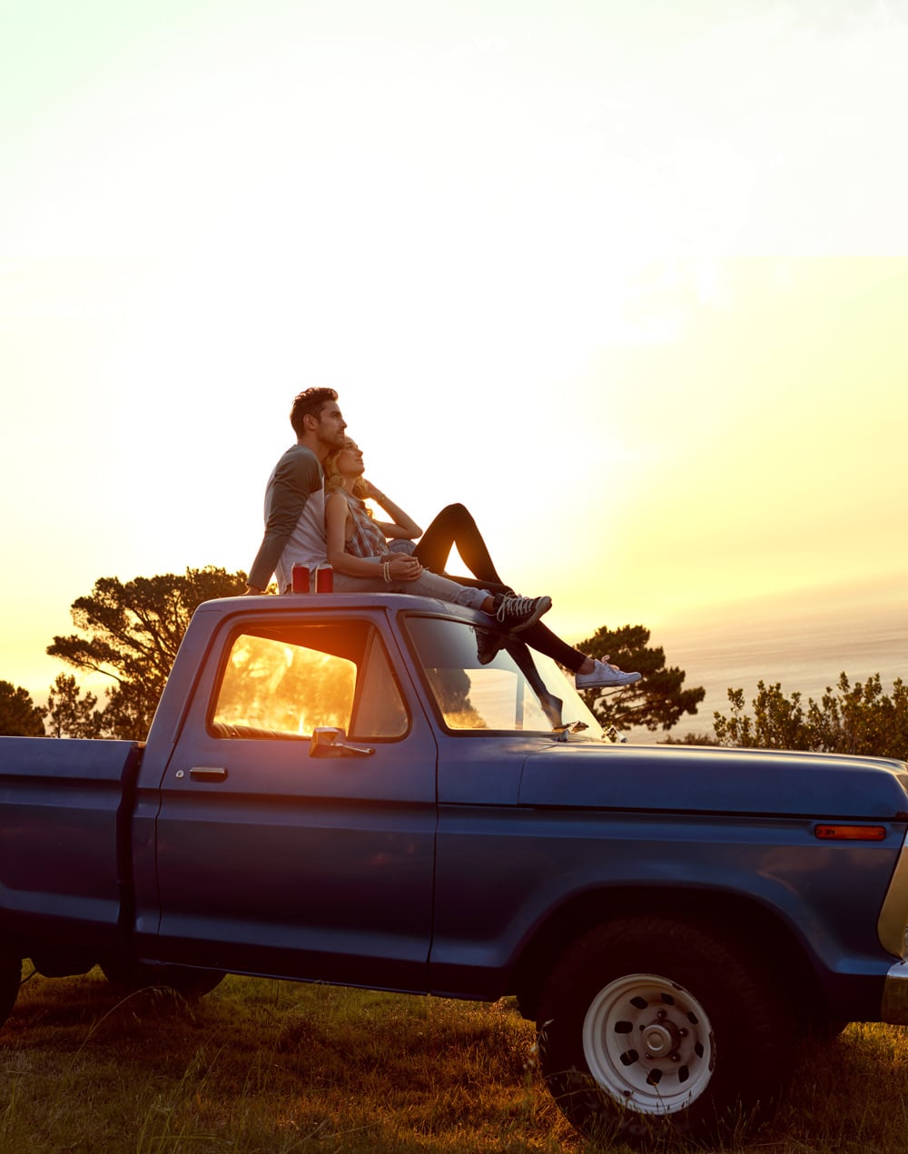 Young Couple sitting on top of their converted 4WD truck